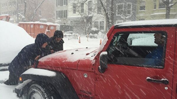 Люди толкают автомобиль, застрявший в снегу