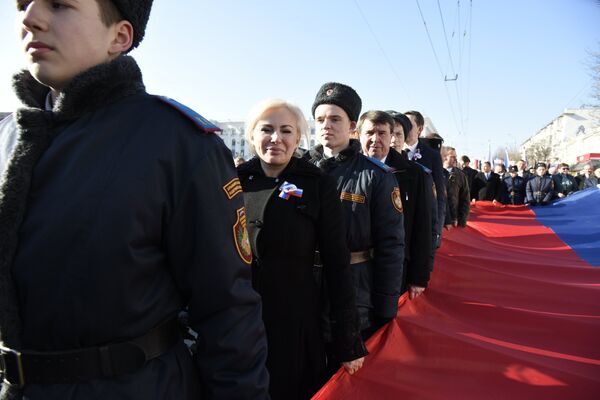 Торжественные мероприятия в Симферополе в честь второй годовщины референдума 2014 года. Начало шествия. Сенаторы от Крыма сенаторы от Крыма Ольга Ковитиди и Сергей Цеков несут флаг России
