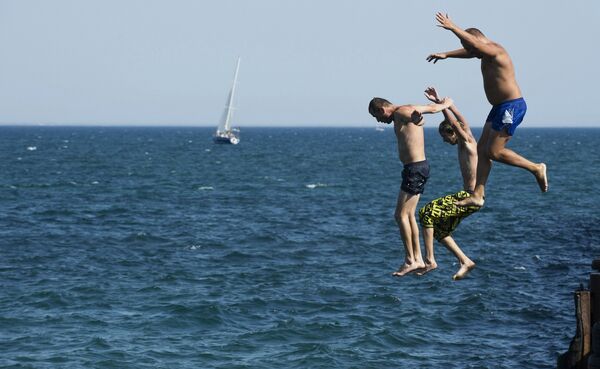 Мужчины прыгают в Черное море в городе Евпатории
