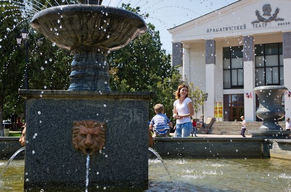 Отдыхающие у фонтана перед зданием драматического театра имени Пушкина в Керчи