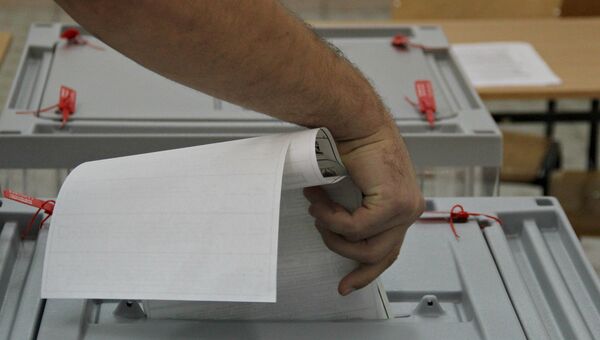 Мужчина бросает бюллетень в избирательную урну