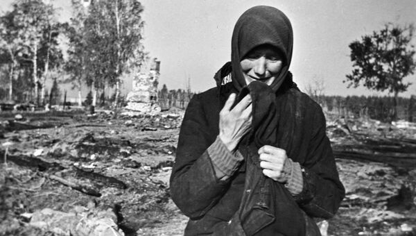 Женщина плачет на развалинах родного села, сожженного фашистами во время Великой Отечественной войны