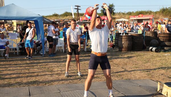 Мужчина поднимает гири на площадке для силовых упражнений, установленной на территории музыкального фестиваля ZBFest в Балаклаве (Севастополь)