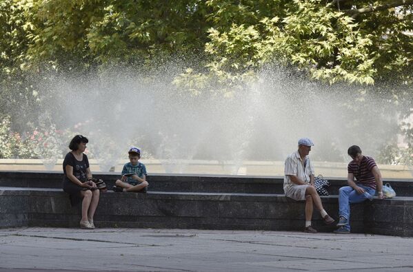 Люди отдыхают в тени у фонтанов в районе Государственного совета РК в Симферополе