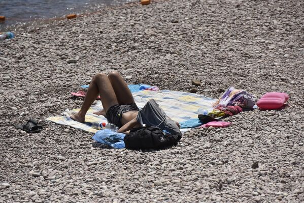 Мужчина на пляже Гурзуфа прячется от дневного зноя под вещами