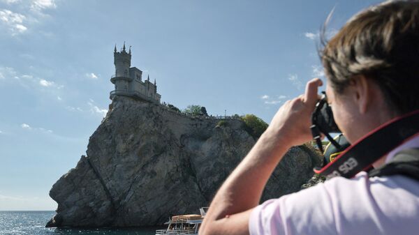 Турист фотографирует замок Ласточкино гнездо