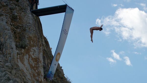 Спортсмен выполняет прыжок на тренировочной базе для занятия хай-дайвингом на скале Дива в Симеизе в Крыму.