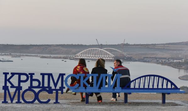 Люди на скамейке Крымский мост наблюдают за морской операцией установки железнодорожной арки моста через Керченский пролив