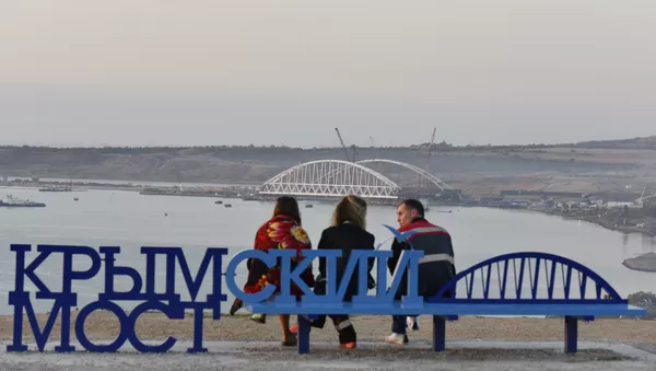 Люди на скамейке Крымский мост наблюдают за морской операцией установки железнодорожной арки моста через Керченский пролив