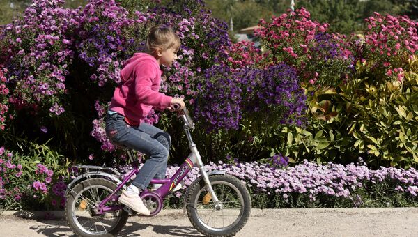 Девочка катается на велосипеде в ботаническом саду КФУ в Симферополе