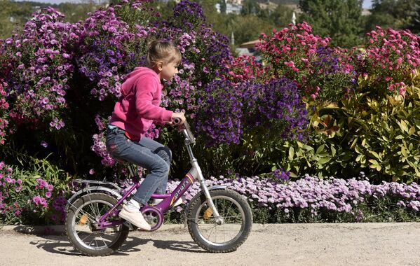 Девочка катается на велосипеде в Ботаническом саду Крымского федерального университета им.Вернадского в Симферополе