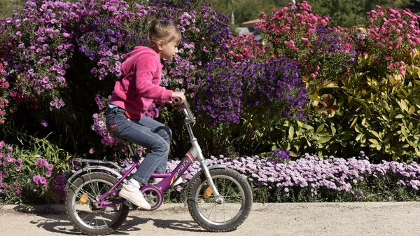 Девочка катается на велосипеде в Ботаническом саду Крымского федерального университета им.Вернадского в Симферополе