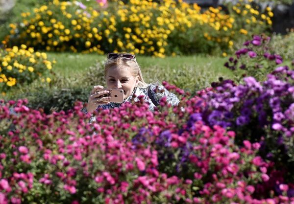 Женщина фотографирует цветы в Ботаническом саду Крымского федерального университета им.Вернадского в Симферополе