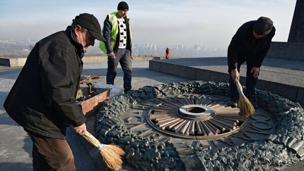 Работники Киевгаз очищают вновь залитый цементом мемориал Вечный огонь в парке Славы в Киеве