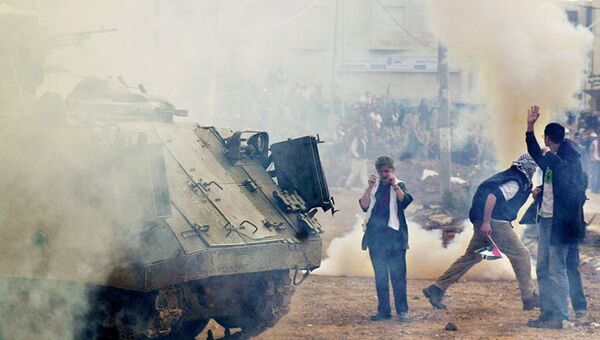 Пропалестинские демонстранты вблизи израильского бронетранспортера во врмя митинга в городе Рамалла на Западном берегу. 27 декабря 2001 года