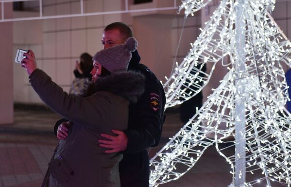 Люди фотографируются на фоне новогодней композиции на площади Ленина в Симферополе