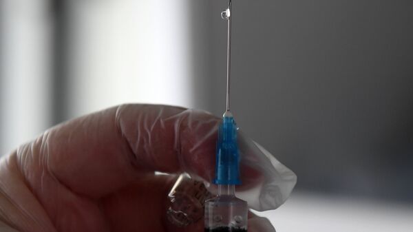 Сотрудник пункта вакцинации готовится делать прививку против гриппа