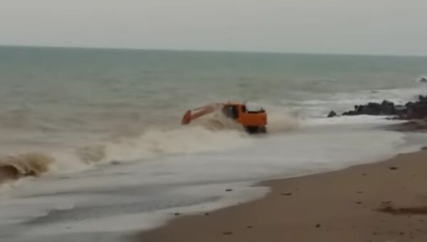 Скриншот с видео в YouTube В Крыму экстремал искупал экскаватор в штормящем море