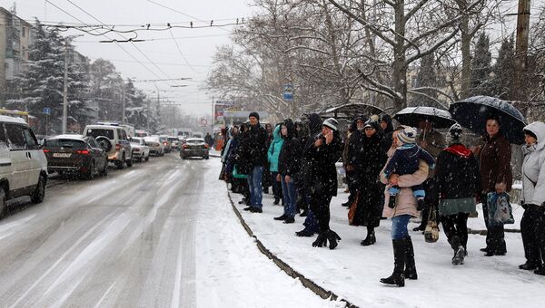 Люди под снегопадом ожидают общественный транспорт на остановке в Севастополе. 27 февраля 2018