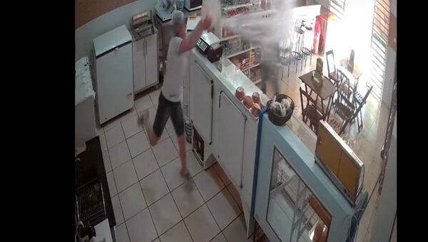 Скриншот с видео, где женщина в Бразилии окатила грабителя магазина водой из ведра