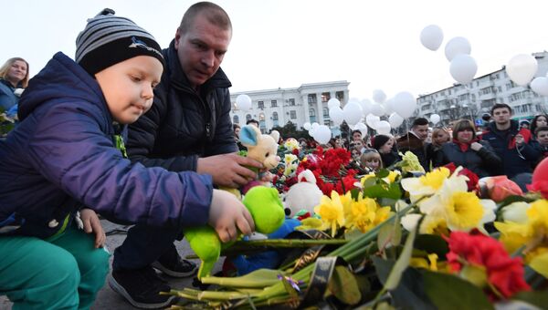 Люди несут цветы и игрушки к импровизированному мемориалу на площади им. Ленина в Симферополе в память о погибших на пожаре в ТЦ Кемерово