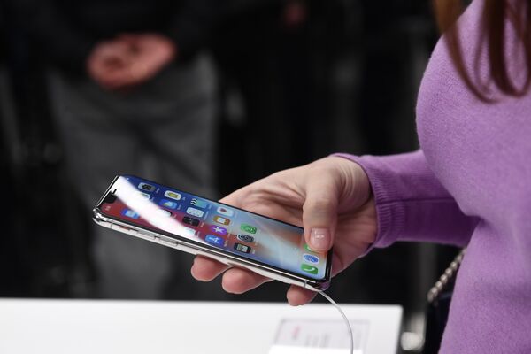 Покупательница рассматривает новый смартфон iPhone X в магазине re:Store в Москве Покупательница рассматривает новый смартфон iPhone X в магазине re:Store в Москве
