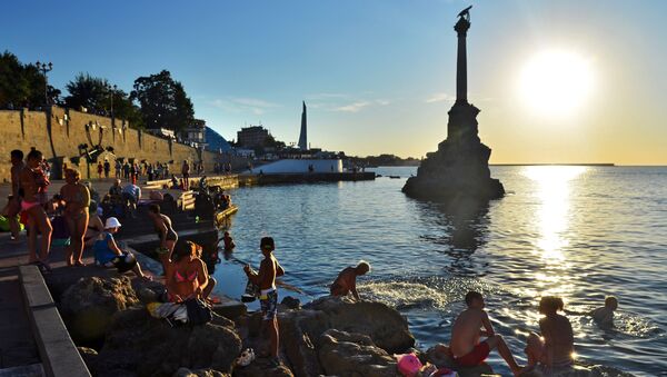 Отдыхающие и местные жители купаются у памятника затопленным кораблям на закате недалеко от Приморского бульвара в Севастополе