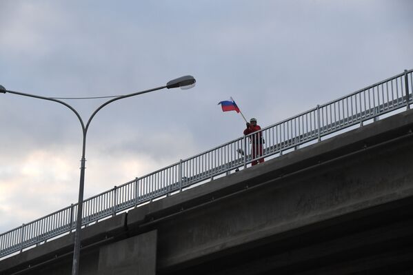 Мужчина с флагом России приветствует первых участников движения по Крымскому мосту. 16 мая 2018