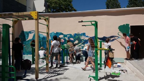 Дизайнеры вместе с воспитанниками детской художественной школы Алушты оформляют стены спортивной площадки под открытым небом на новой набережной Профессорского уголка