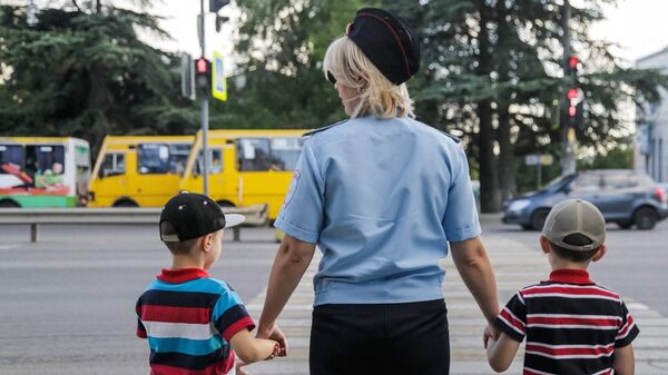 Сотрудник полиции переводит детей через пешеходный переход в Симферополе 