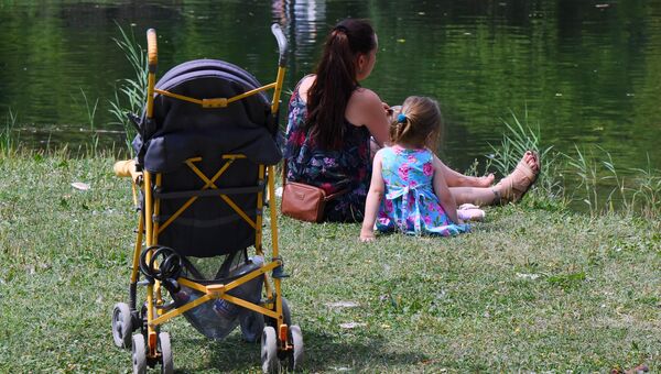 Женщина с ребенком отдыхают у пруда в парке им. Гагарина в Симферополе