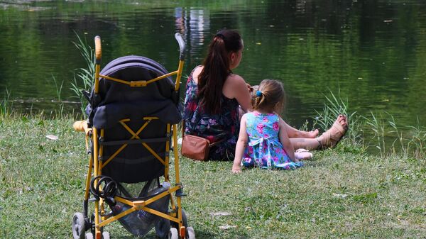 Женщина с ребенком отдыхают возле озера в парке им. Гагарина в Симферополе