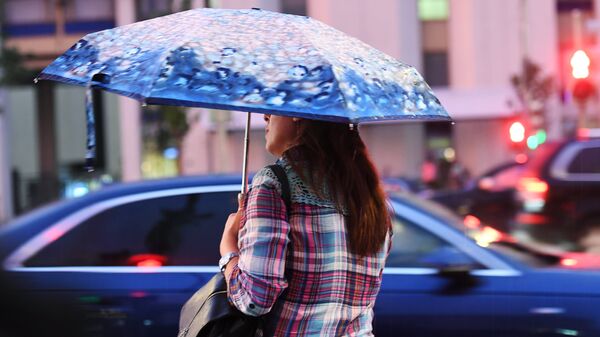 Женщина переходит дорогу во время дождя.
