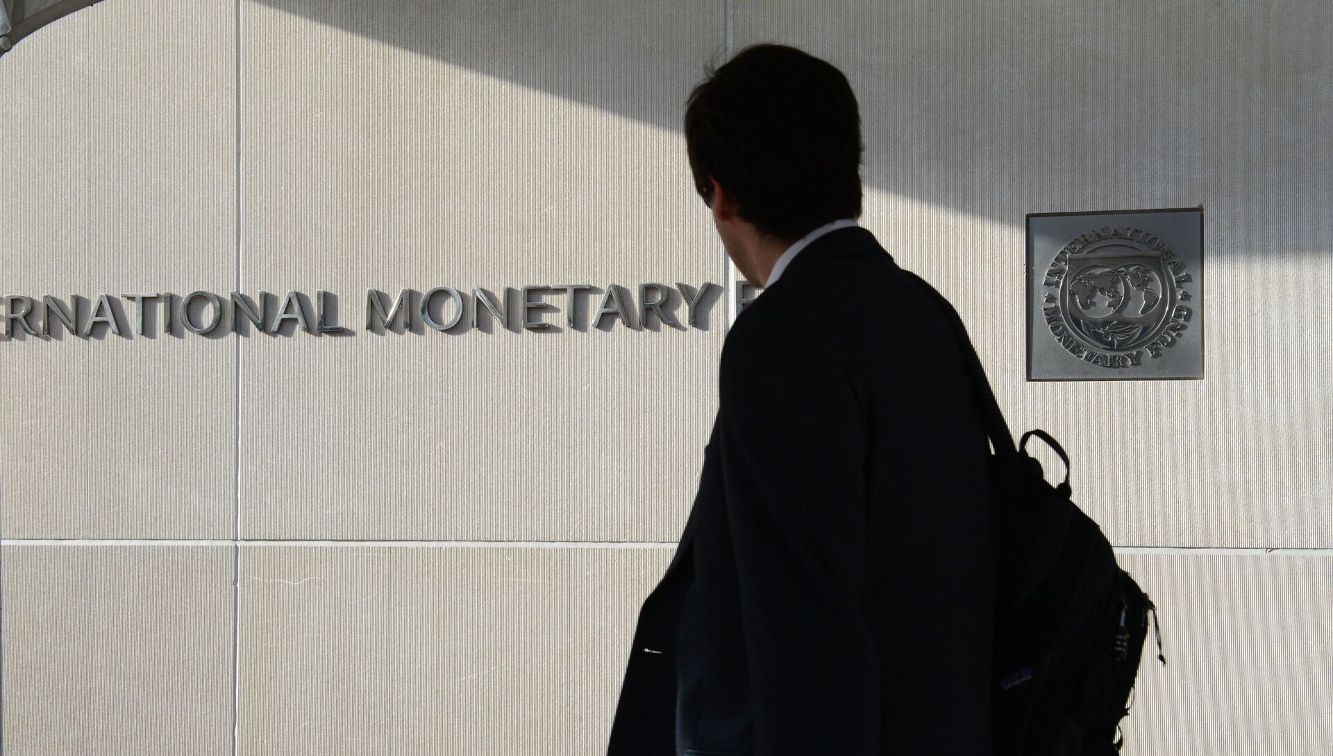 Мужчина у здания Международного валютного фонда смотрит на логотип МВФ на стене. - РИА Новости, 1920, 02.02.2021