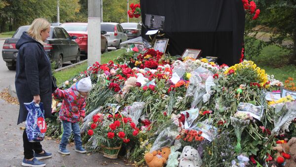 Женщина с ребенком возле народного мемориала в память о погибших в Керченском политехническом колледже
