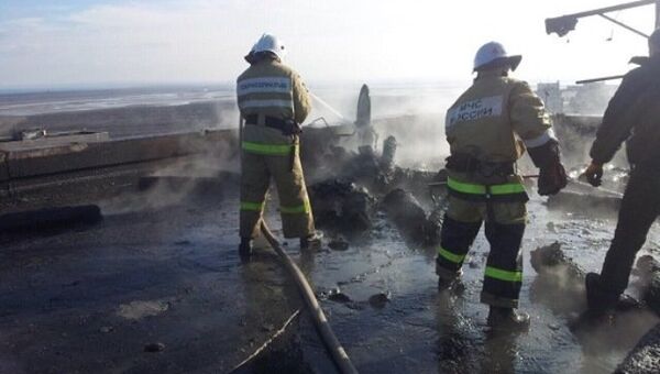 Сотрудники МЧС тушат пожар на месте взрыва газовых баллонов на крыше девятиэтажного дома в Щелкино