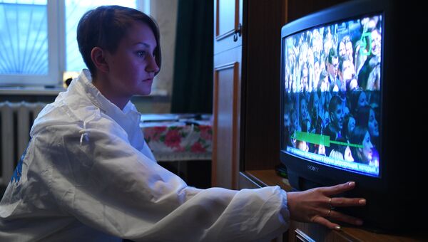 Девушка-волонтер помогает настроить работу телевизора с приставкой для цифрового вещания