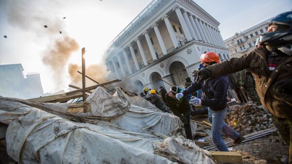 Сторонники оппозиции кидают камни на площади Независимости в Киеве, где начались столкновения митингующих и сотрудников правопорядка