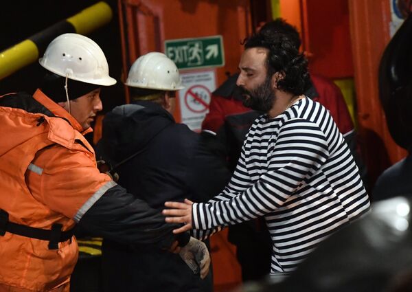Иностранный моряк (справа), спасенный с одного из горящих танкеров, покидает буксир морской спасательной службы Меркурий в торговом порту Керчи. 22 января 2019