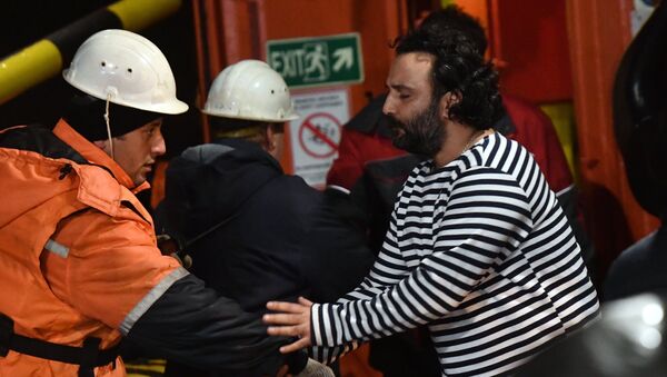 Иностранный моряк (справа), спасенный с одного из горящих танкеров, покидает буксир морской спасательной службы Меркурий в торговом порту Керчи. 22 января 2019