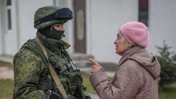 Местная жительница разговаривает с военнослужащим в селе Перевальное недалеко от Симферополя.