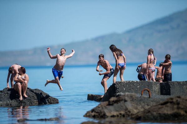 Отдыхающие прыгают в воду с волнорезов в Новом Свете, Крым