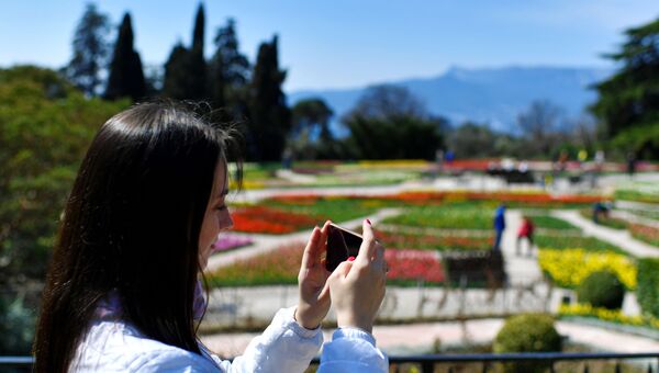 Девушка фотографирует в Никитском ботаническом саду в Крыму