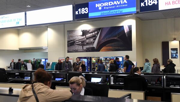 Женщина покупает авиабилет на рейс авиакомпании Нордавиа — региональные авиалинии в аэропорту Домодедово