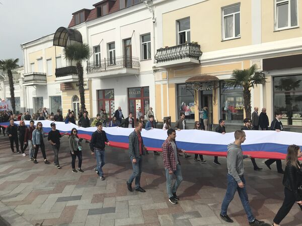 Участники первомайской демонстрации в Ялте несут 20-метровое полотно флага РОссии. 1 мая 2019
