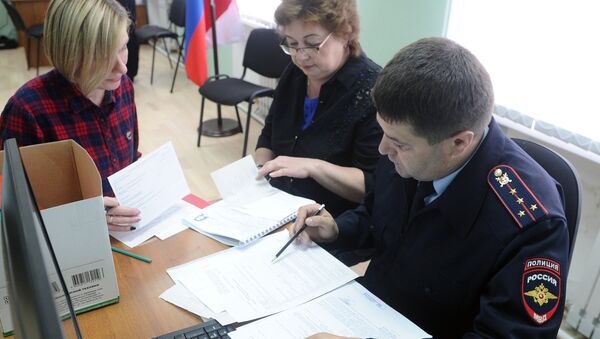 Сотрудник полиции и посетители в центре выдачи российских паспортов жителям ДНР и ЛНР