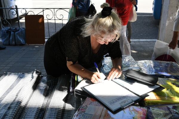 Женщина подписывает протокол, составленный на нее по факту ведения стихийной торговли в центре Симферополя Женщина подписывает протокол, составленный на нее по факту ведения стихийной торговли в центре Симферополя