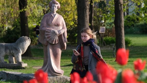 Девушка смотрит в мобильный телефон на Крымской набережной в парке искусств Музеон в Москве.