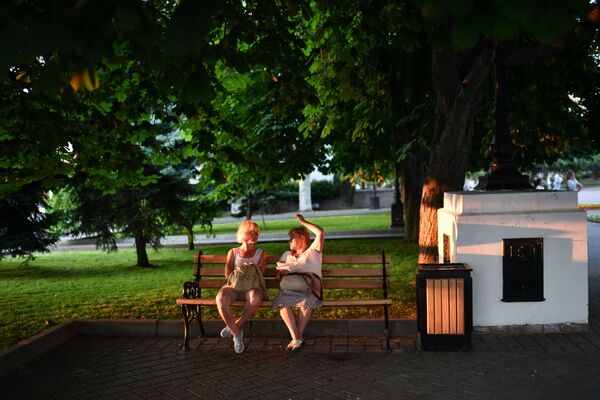 Отдыхающие сидят на скамейке в парке в Севастополе в Крыму