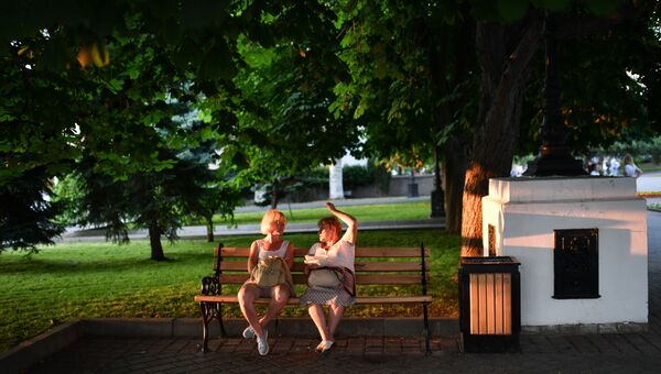 Отдыхающие сидят на скамейке в парке в Севастополе в Крыму